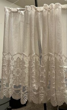 a white curtain with lace on it hanging in front of a window