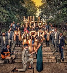 a group of people posing for a photo with the words you marry spelled in gold letters