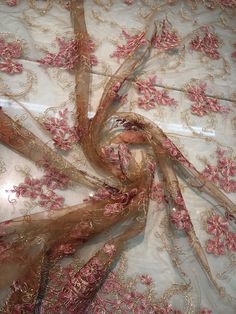 the fabric has pink flowers on it, and is very intricately embroidered with gold thread