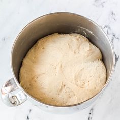 a metal pot filled with dough on top of a white counter