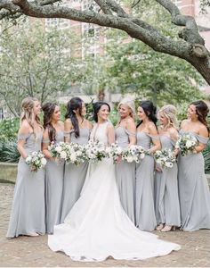 a group of women standing next to each other in front of a tree with white flowers