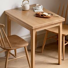 a wooden table with two chairs next to it and a tea pot on the table