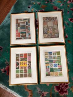 four framed pictures with different designs on them sitting on a floral print table cloth next to each other