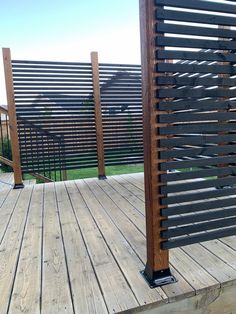 a wooden deck with black iron railings and wood slats on the top level