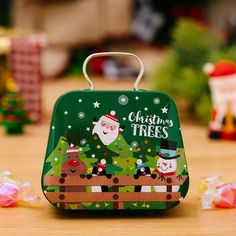 a christmas tree lunch box sitting on top of a wooden table next to candy candies