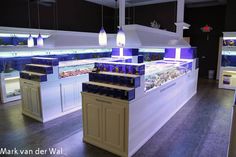 an empty fish market with blue lights on the ceiling and white counter tops in front of it