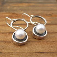 A minimal and modern look with a nod to old school pearl earrings. These sterling silver and pearl earrings are set in a modern round shadow bezel style and hang from sculptural open circles. The cultured pearl is half drilled on the bottom and glued to a sterling post soldered to the necklace for durability. You will get a lot of compliments when wearing this mini art piece. To see all my pearl jewelry go here: https://www.etsy.com/shop/marmarModern?ref=seller-platform-mcnav&section_id=1328 Modern Pearl Pendant Earrings, Modern Drop Pearl Earrings, Modern Pearl Drop Earrings With Pendant, Modern Round Pearl Earrings, Modern Sterling Silver Pearl Earrings As Gift, Modern Round Sterling Silver Pearl Earrings, Modern Sterling Silver Pearl Earrings For Gift, Modern Sterling Silver Pearl Earrings, Modern Pearl Drop Earrings For Anniversary