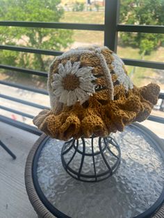 a crocheted hat sitting on top of a glass table next to a window