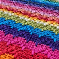 a multicolored crocheted blanket is laying on the floor