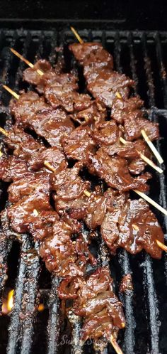 several skewered meats are being cooked on the grill