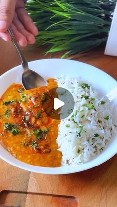 a person is spooning food out of a bowl with rice and greens on the side