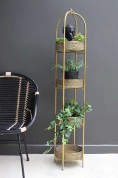 a black chair sitting next to a gold plant stand