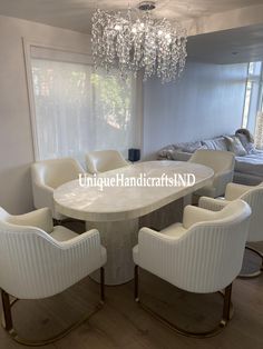 a dining room table with white chairs and a chandelier