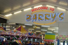 the welcome sign to barry's is lit up in blue and yellow at night