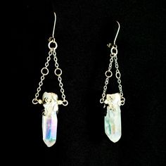 These beautiful angel aura quartz earrings are a dazzling addition to your jewelry collection. The rainbow glimmer on the crystal shimmers as the light catches it at different angles. Each crystal has two hand molded flower charms that wrap around the crystal and the silver finish give them an elegant yet bold feel. These are real gemstone earrings that dangle and have some weight to them. These earrings are not for those who are sensitive to heavily weighted earrings, but if you like to flaunt Iridescent Pierced Drop Earrings, Handmade Mystical Crystal Jewelry, Iridescent Dangle Crystal Earrings For Pierced Ears, Mystical Crystal Jewelry Gift, Iridescent Crystal Dangle Jewelry, Mystical Silver Jewelry With Ear Wire, Silver Mystical Jewelry With Ear Wire, Iridescent Metal Drop Earrings, Iridescent Metal Dangle Jewelry