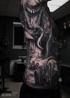 a man's back covered in black and grey tattoos with an image of a monster