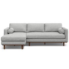 a small sectional couch with pillows on the top and bottom, sitting in front of a white background