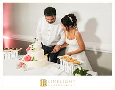 a bride and groom cutting their wedding cake at the reception table in front of some cupcakes