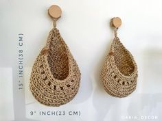 a pair of crocheted earrings hanging from hooks on a white wall next to a sign