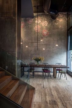 a dining room table with chairs and flowers on the wall next to glass railings