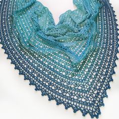 a blue crocheted shawl is shown on a white surface with an openwork design