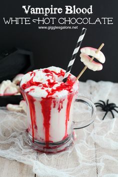 a red and white drink with marshmallows on the rim in a glass mug