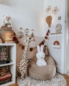 a stuffed giraffe sitting on top of a bean bag chair in a child's room