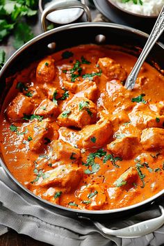 a pan filled with chicken curry and garnished with parsley on the side