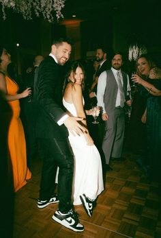 a man in a tuxedo is dancing with a woman on the dance floor