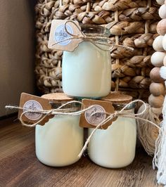 three mason jars with labels on them sitting next to a basket