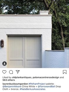 an instagramted photo of a white brick house with two garage doors