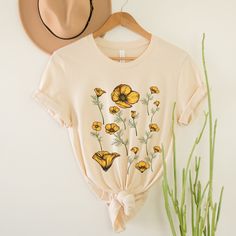 Botanical California flower tshirt for women is a great addition to any girl's wardrobe this season.  Beautiful vintage style cottagecore yellow poppy florals make this shirt truly remarkable; it will look great when wearing it.   Great gift for nature lovers, gift for mom, gift for grandma, gift for friends, gift for gardeners. OUR ADULT SHIRTS our designs are printed on Bella + canvas unisex shirts.  these shirts are 100% soft and light weight cotton for a soft and comfortable feeling, ribbed Trendy Tops For Summer Garden Party, Vintage Relaxed Fit T-shirt With Plants Print, Summer Cotton Floral Print T-shirt, Trendy Tops For Spring Garden Party, Summer Floral Embroidery Relaxed Fit T-shirt, Vintage Cotton T-shirt With Plant Print, Cottagecore Floral Print Top For Garden Party, Spring Organic Cotton Tops, Cottagecore Printed T-shirt With Relaxed Fit