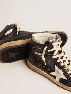 A reinterpretation of high-top sneakers with an authentic soul: inspired by our Ball Star model, our Sky-Star sneakers have an American college vibe and a feel of the basketball scene of the Eighties. This model, with a black nappa-leather upper, features a white nappa-leather star and the Golden Goose signature on the neck of the ankle, a reference to the childhood dream of having your favorite sneakers signed by basketball legends. The cream-colored laces complete the look. Golden Goose Sky Star, Star Font, Leather Street Style, Michel Vivien, Silly Clothes, The Golden Goose, Golden Family, Celine Daoust, Childhood Dream