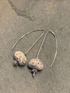 Drilled natural granite beach stone hangs at the bottom of wishbone-shaped earrings of 21 g sterling silver wire and beads.  These earrings dangle about 2" from the top. Jewelry pieces in my "by the sea" collection feature beach stones that have been smoothed by many years spent crashing against the shore. These stones are in their natural state (versus tumbling) which retains their energy. Over time they become polished by the wearer's skin oils making each piece very individual and personal. When worn, the stones absorb and retain heat from the body and have been said to offer healing qualities to the wearer. See other earrings in: https://www.etsy.com/shop/thegildedlilystore?section_id=17945716&ref=shopsection_leftnav_3 Beach Stones Jewelry, Beach Stones, Jewelry Sterling Silver, River Rock, Sea Beach, By The Sea, Stone Earrings, Silver Wire, Stone Jewelry