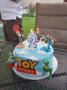 a birthday cake with toy story characters on it sitting on a table in the backyard