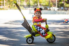 a young boy riding a tricycle with mickey mouse ears on it's head