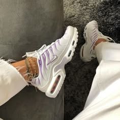 a person wearing white pants and purple nike air max sneakers with gold chains on their ankles