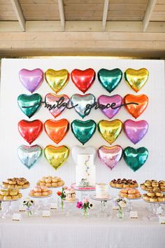 a table topped with lots of heart shaped balloons next to cakes and desserts on plates