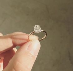 a person holding a ring with a diamond in it's middle and the other hand