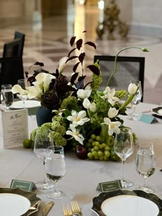 the table is set with white and green flowers, silverware, and wine glasses