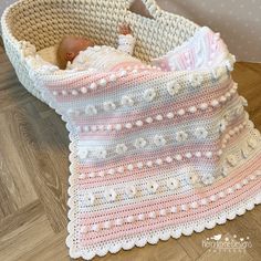 a crocheted basket with a baby in it and a blanket on the floor