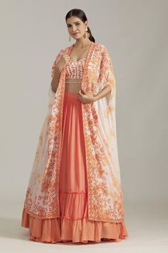 Orange cape with dori embroidered floral motifs on tie dye base. Comes with embroidered tasselled blouse and tiered hem lehenga.
Components: 3
Pattern: Embroidered
Type Of Work: Sequin,Cutdana
Neckline: Cape: Open, Blouse: Sweetheart
Sleeve Type: Cape: Cape sleeves, Blouse: Sleeveless
Fabric: Georgette
Color: Orange
Other Details: 
Attached lining
Closure: 
Blouse: Back hook
Lehenga: Side closure
Weight (in grms): 300
Lehenga Length(in inches): 42
Occasion: Mehendi and Haldi,Sangeet - Aza Fashio Bohemian Sets With Intricate Embroidery For Reception, Spring Reception Sets With Dupatta, Spring Choli With Sheer Dupatta In Georgette, Spring Georgette Choli With Sheer Dupatta, Bohemian Wedding Sharara With Floral Embroidery, Bohemian Floral Embroidery Sharara For Wedding, Spring Bollywood Embroidered Lehenga, Spring Choli With Dupatta For Reception, Gown With Multicolor Embroidery And Dupatta