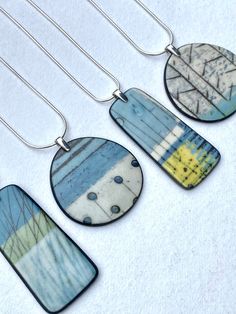 four necklaces with different designs on them sitting on a white surface, one is blue and the other is yellow