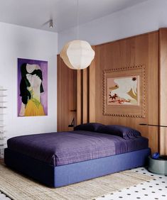 a bedroom with a purple bed in the middle and a painting on the wall behind it