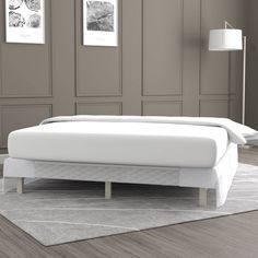 a white bed sitting on top of a hard wood floor next to a gray wall