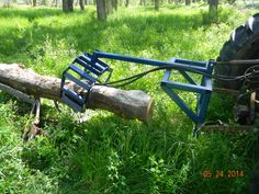 a large log laying in the grass next to a tractor