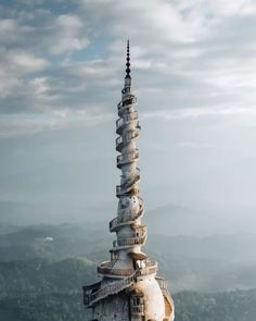 a very tall tower with a clock on it's side in the middle of some hills