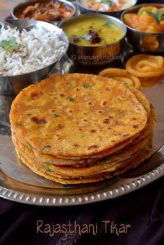 some food is on a silver plate with rice and other foods in bowls around it