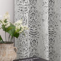 a vase filled with flowers sitting next to a wallpaper covered in grey and white designs