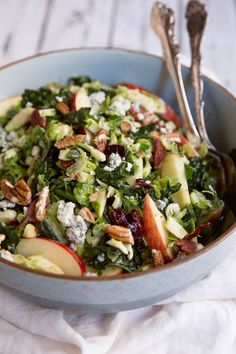 a salad with apples, cheese and nuts in a blue bowl on a white cloth